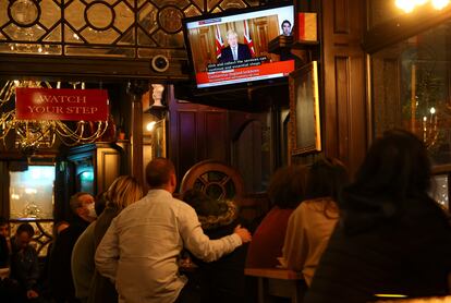 Varios clientes de un pub atienden al discurso del primer ministro británico.