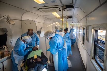 Los dentistas del 'Phelophepa' atienden a un paciente en uno de los vagones durante una parada en Kroonstad. Este tren ha dado servicios de atención primaria a zonas de bajos recursos en Sudáfrica desde 1994.