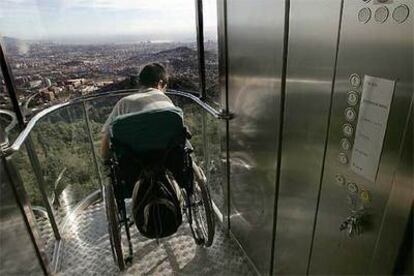 Un joven discapacitado oberva Barcelona tras subir en el ascensor adaptado del Tibidabo.