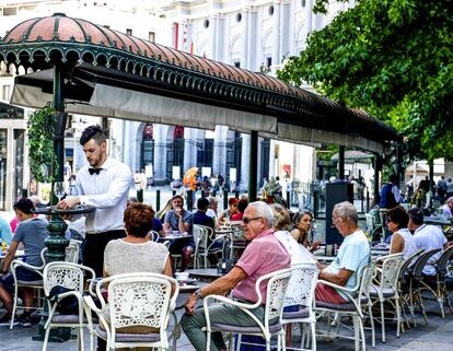 Un camarero sirve café en una terraza en Madrid.