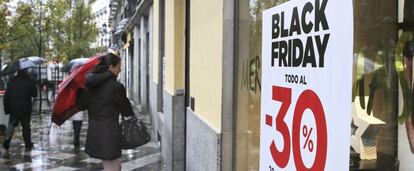 Un cliente pasa junto un escaparate con publicidad del Black Friday