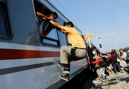 La Policía de Croacia anunció a última hora del jueves el cierre de siete pasos fronterizos con Serbia, incluido el de Tovarnik, por donde más de 11.000 refugiados han entrado al país en apenas dos días como parte de su intento desesperado por alcanzar el centro de Europa. En la imagen, un refugiado intenta subir a un tren por la ventana de un vagón en la estación croata de Tovarnik, el 18 de septiembre de 2015.