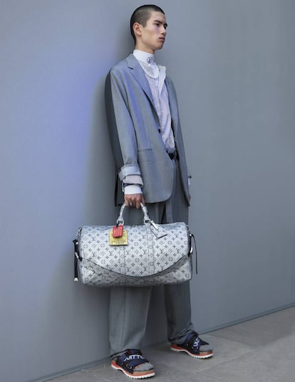Traje desestructurado, sandalias, camisa, camiseta deportiva de cuello alto y bolsa Keepall, todo, perteneciente a la colección Primavera Verano 2018 de Louis Vuitton.