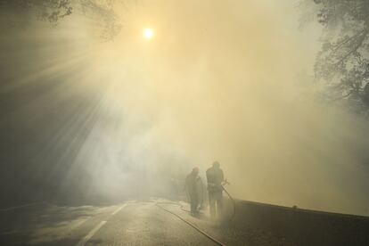 Bomberos apagan las llamas, cerca de Gonfaron, en medio de una columna de humo, este martes.