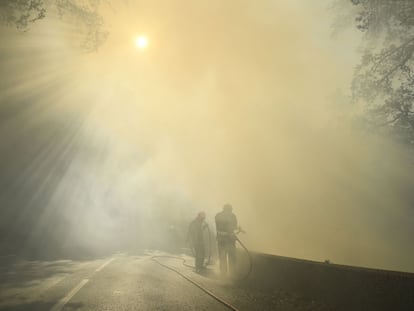Bomberos apagan las llamas, cerca de Gonfaron, en medio de una columna de humo, este martes.