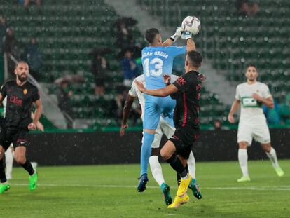 ELCHE, 10/10/2022.- El portero del Elche Edgar Badía (c) despeja un balón junto al argentino Braian Cufré, del Mallorca, durante el partido de la jornada 8 de Liga en Primera División que Elche CF y Real Mallorca disputan hoy lunes en el estadio Martínez Valero, en Elche. EFE/ Biel Alino
