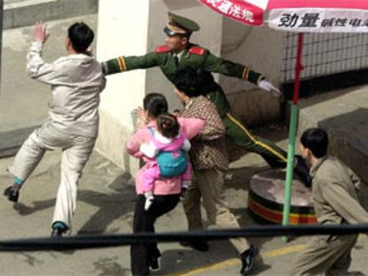 Un policía chino intenta impedir la entrada de unos norcoreanos en el consulado japonés en Shenyang (noreste de China).