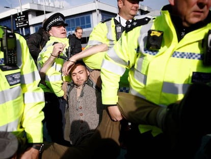 Varios policías detienen a un activista de Extinction Rebellion en el aeropuerto London City, este jueves.