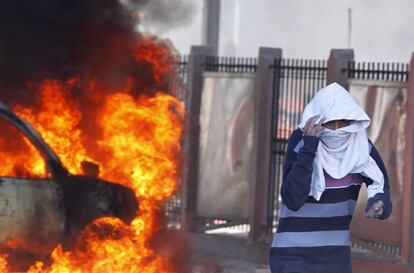 Un manifestante se protege de los gases lacrimógenos durante la protesta en las cercanías del cementerio donde ha sido enterrado el opositor Belaid.