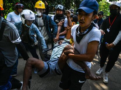 Varios manifestantes transportan a un herido durante la represión violenta en Yangón este viernes.