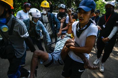 Varios manifestantes transportan a un herido durante la represión violenta en Yangón este viernes.