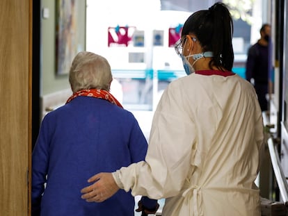 Una trabajadora de una residencia de mayores ayuda a una paciente, este lunes, en Madrid.