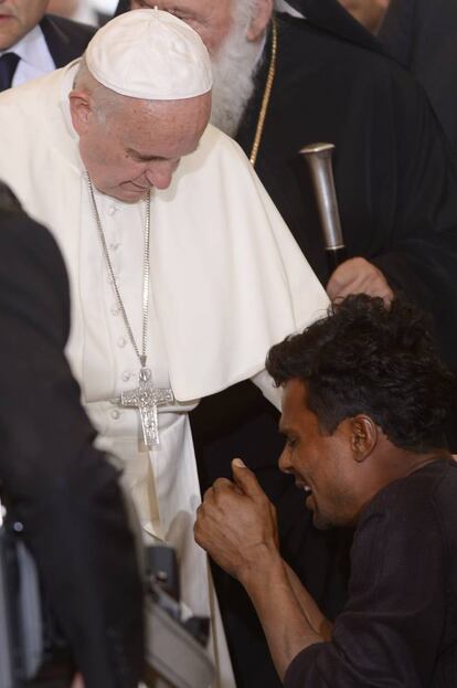 Un hombre arrodillado llora frente al papa Francisco en el campo de refugiados de Moria.