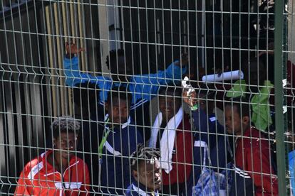 Migrantes saludan desde el interior del CETI de Ceuta. 