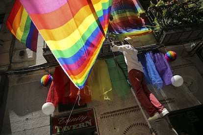 Un empleado de un bar cuelga una bandera en la fachada de un edificio de Chueca.