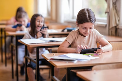 Niños juegan con su móvil en clase.