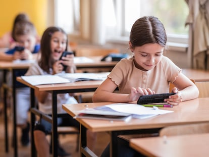 Niños juegan con su móvil en clase.