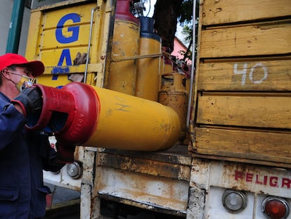 Un repartidor de tanques de gas sube al camión un cilindro vacío.