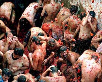 Los participantes en la <I>Tomatina</I> se protegen de los impactos.