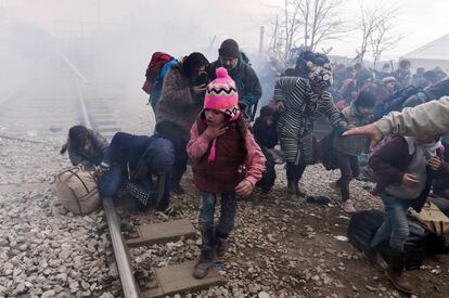 Los policías macedonios han lanzado varias rondas de gases lacrimógenos contra la multitud, después de que echaran abajo una puerta metálica, y hacia la vía de ferrocarril donde los inmigrantes se habían sentado negándose a moverse, para reclamar su entrada en el país. En la imagen, una niña se protege de los gases lacrimógenos lanzados por la policía en Indomeni (Grecia).