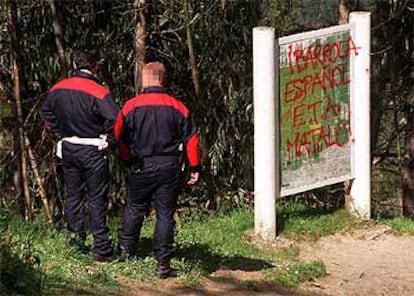 Dos <i>ertzainas</i> observan las amenazas contra Ibarrola en el bosque de Oma.