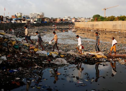 Habitantes de Bombay cruzan un canal de agua contaminada.