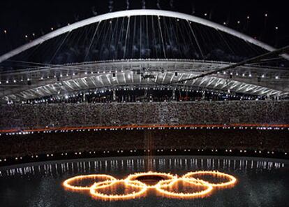 Una vista general del estadio con los aros olímpicos ardiendo sobre el lago.