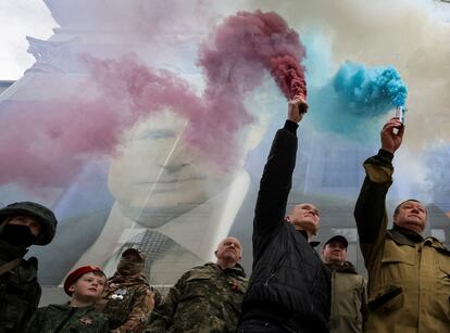 Participants burn flares in front of a banner with a portrait of Russian President Vladimir Putin during a patriotic flash mob marking the ninth anniversary of Russia's annexation of Crimea on March 17, 2023.