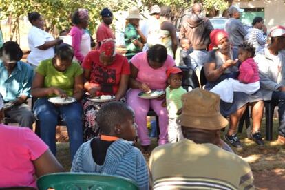 Mineros y mujeres de los trabajadores de las minas en huelgas comen en el patio de la iglesia de Wonderkop.