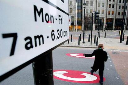 Un hombre cruza por una señal de comienzo de zona de peaje en una calle de Londres.