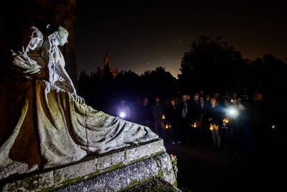 Participantes en una visita nocturna contemplan una tumba labrada por el escultor Francisco Asorey en el cementerio de Vigo.