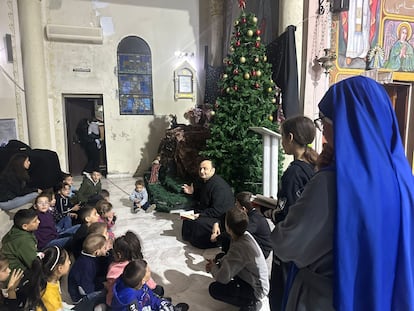 El padre Gabriel Romanelli (sentado en el centro) se dirige a un grupo de niños en la iglesia de la Sagrada Familia de Gaza, donde están refugiados varios centenares de cristianos. Fotografía tomada en diciembre de 2024 y cedida por la parroquia.