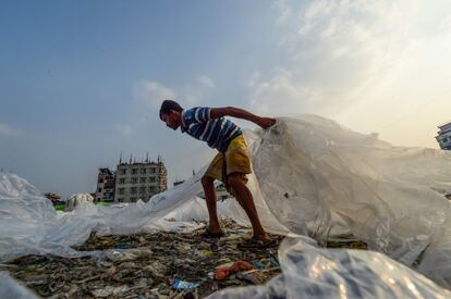 Un trabajador recoge bolsas de plástico usadas para transportar productos químicos industriales para que se sequen junto al río Buriganga en Daca (Bangladés), el 21 de noviembre.