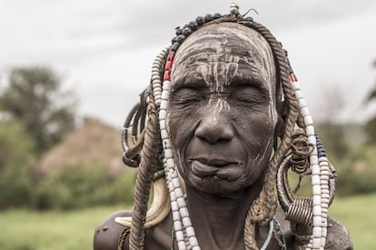 En la imagen, una anciana mursi del poblado de Marreke posa con los ojos cerrados y un tocado improvisado mediante la combinación de unos collares de cuentas de plástico y el bocado de una res. Se aprecia el cosido del labio inferior, acción que el Gobierno etíope intenta suprimir.