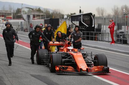 Los mecánicos de la escudería McLaren empujan el coche del piloto belga Staffel Vandoorne depués de que su motor se parase a la entrada del 'pit lane'.