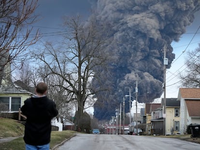 Un hombre toma una foto de la columna de humo provocada por la explosión controlada en East Palestine, Ohio el 6 de febrero 2023