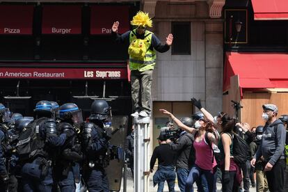 Um membro dos 'coletes amarelos', em cima de uma barreira que separa a polícia dos manifestantes no 1º de maio em Paris.