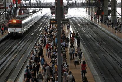 Viajeros esperando el tren en los andenes en la estación de Atocha
