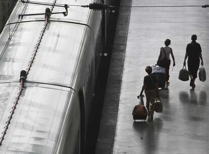 Tres pasajeros afectados por los retrasos caminan por uno de los andenes de la estación de Atocha de Madrid.