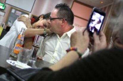Julio corteja a Lupita mientras una de las participantes de la caravana les graba con su móvil.