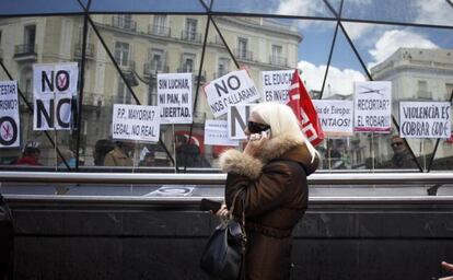 A woman walks by protestors in Madrid&#039;s Puerta del Sol in April.