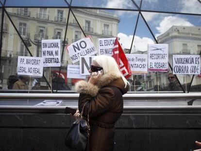 A woman walks by protestors in Madrid&#039;s Puerta del Sol in April.