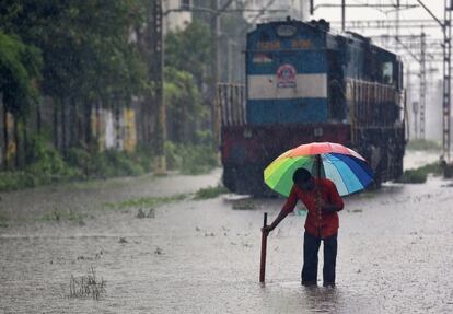 Un viandante intenta desatascar un canal en una vía férrea, durante las fuertes lluvias monzónicas en Mumbai, India.