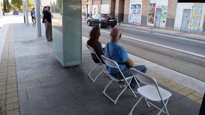 Ante la falta de bancos en la estaci&oacute;n del tranv&iacute;a de avenida de la Academia en Zaragoza, algunos vecinos llevaron sus propias sillas.