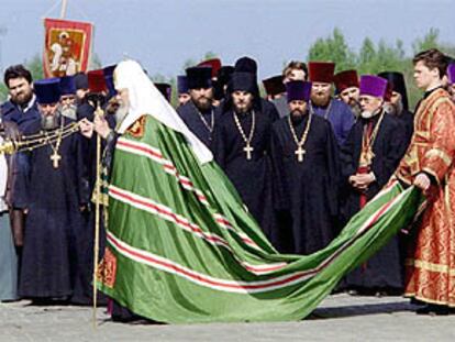 Un ayudante lleva la capa del patriarca de la Iglesia ortodoxa rusa, Alejo II, durante la bendición de un templo.