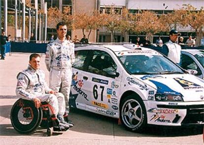 Albert Llovera, en su silla de ruedas, junto a su copiloto y su coche.