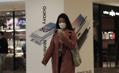 Una mujer consulta su móvil frente a una tienda de Samsung en Seúl.