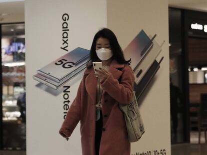 Una mujer consulta su móvil frente a una tienda de Samsung en Seúl. 