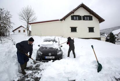 Dos personas retiran la nieve acumulada en su vehículo y despejan la estrada a su casa en la localidad navarra de Espinal, hoy.
