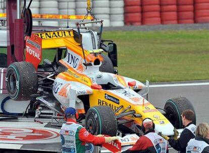 Varios operarios retiran el Renault de 'Nelshino' Piquet del circuito de Nurburgring.